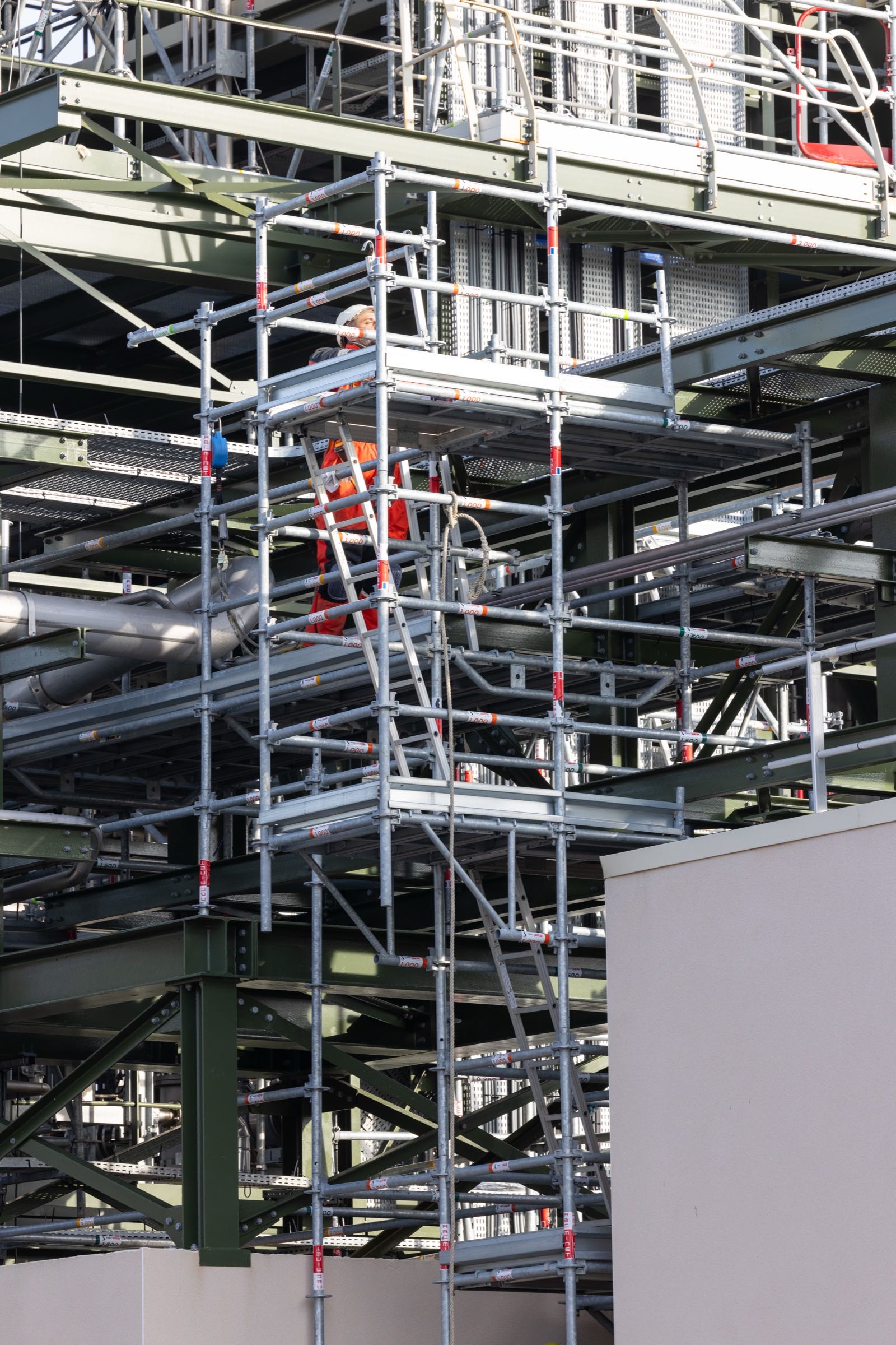 Technicien en ascension sur un échafaudage en milieu industriel